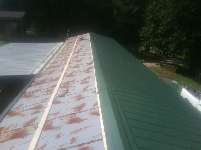 Old rusted panels beside newly installed green metal roofing — Wind Damage Roof Repair by Roofing Brothers in Argyle