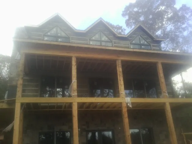 Dormers and porch framing on a large log home under construction — Roof Coating work by our crew in Argyle